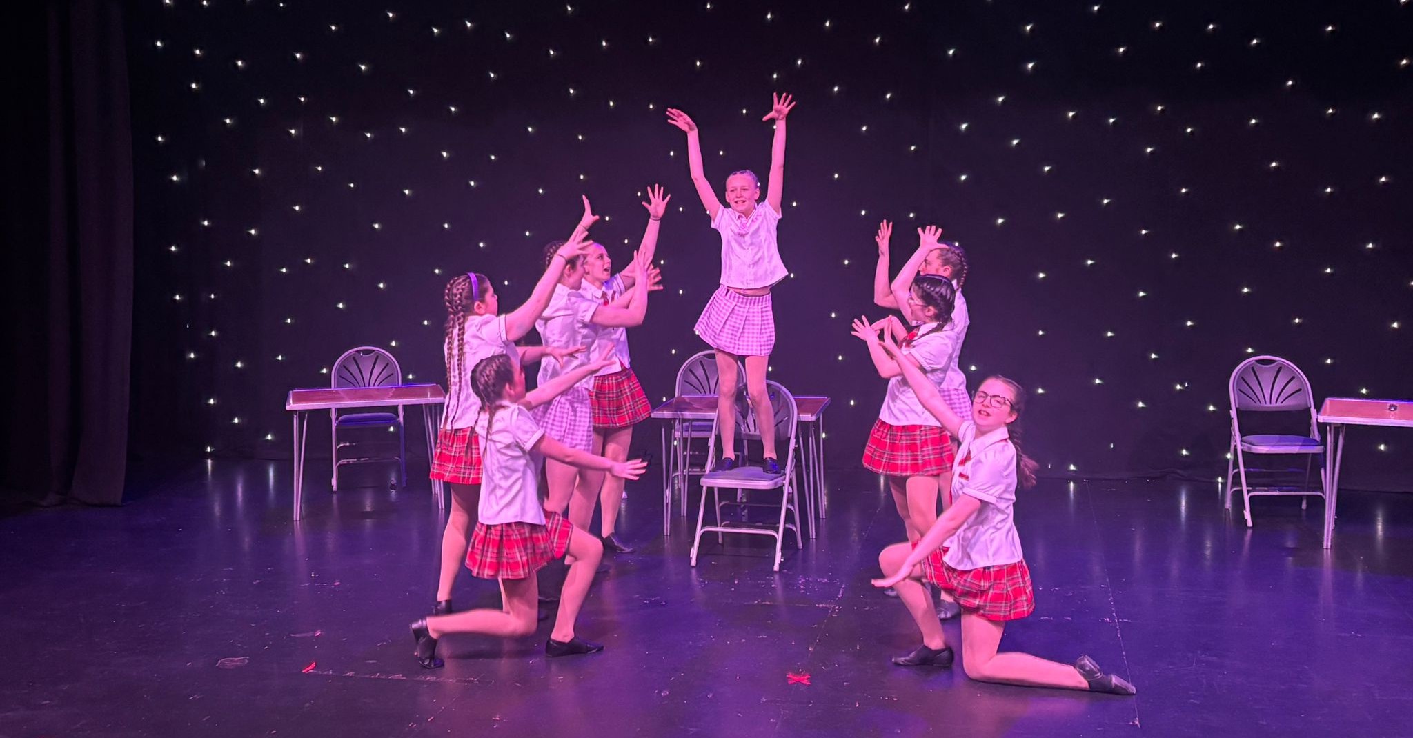 Tap dance students performing synchronized routine on stage